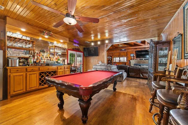 a room with furniture pool table flat screen tv and windows