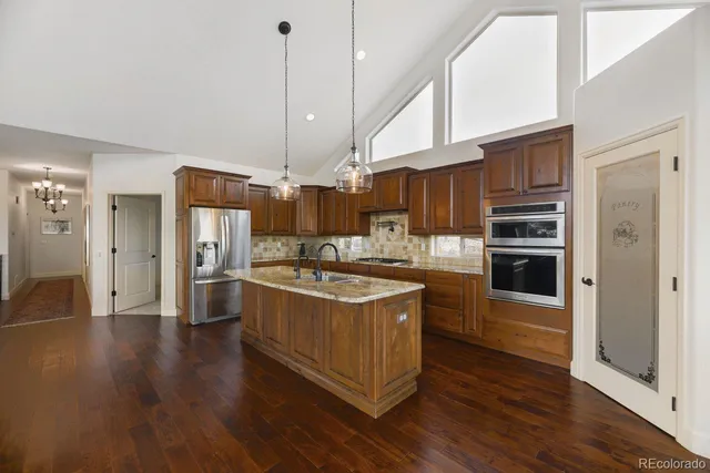 a kitchen with stainless steel appliances granite countertop a sink a stove and a refrigerator
