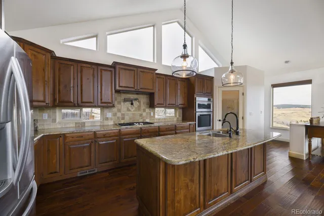 a kitchen with kitchen island granite countertop wooden floors and stainless steel appliances