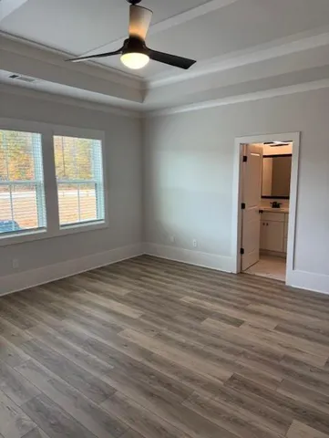an empty room with wooden floor cabinet and windows