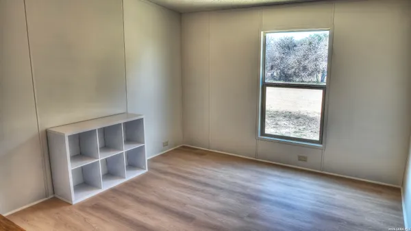 an empty room with wooden floor closet and windows