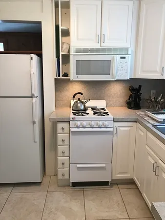 a kitchen with a refrigerator and white cabinets