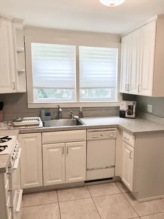 a kitchen with granite countertop white cabinets sink and white appliances