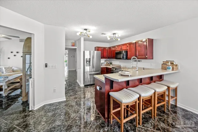 a dinning room with stainless steel appliances kitchen island granite countertop a table chairs and a refrigerator