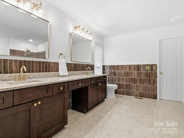a bathroom with a double vanity sink a toilet and a mirror