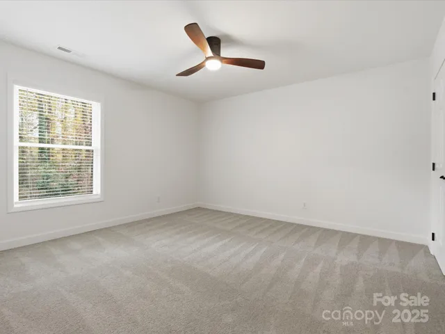 an empty room with a ceiling fan and window