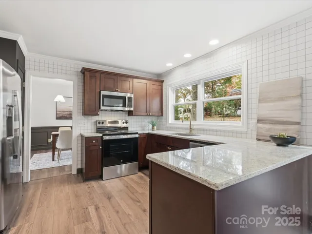 a kitchen with stainless steel appliances granite countertop a sink stove and refrigerator