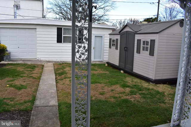 a view of a house with a yard plants and large tree