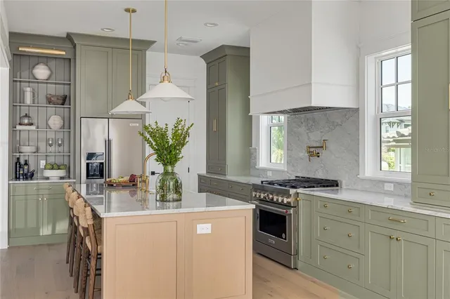 a kitchen with stainless steel appliances granite countertop a stove a sink a refrigerator and a white cabinets