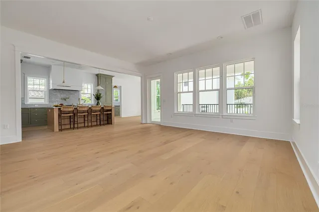 a view of an empty room with window and kitchen view