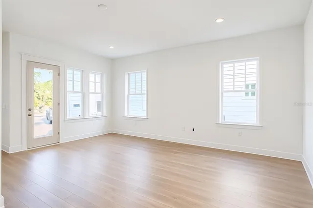 an empty room with wooden floor and windows