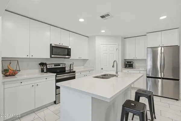 a kitchen with a sink a stove a refrigerator and white cabinets