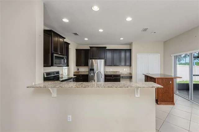a large kitchen with stainless steel appliances kitchen island granite countertop a large cabinets and a counter top space
