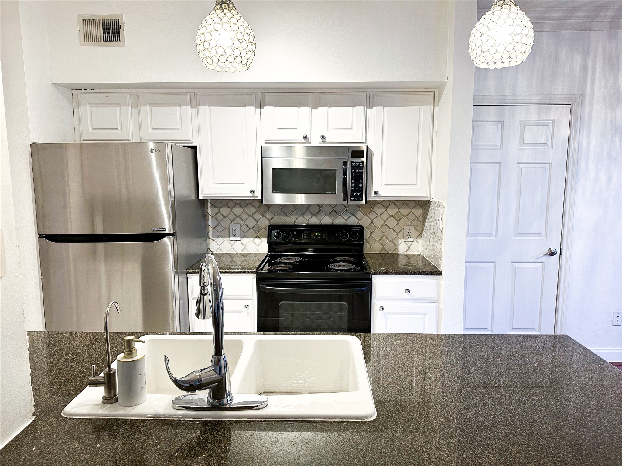 7701 Rialto Boulevard, Unit 1122 Austin, TX 78735 - Photo 5 of 24 Kitchen with white cabinetry and new backsplash