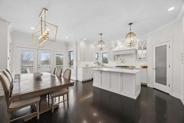 a kitchen with kitchen island a dining table chairs and white cabinets