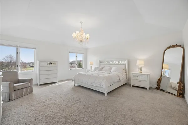 a spacious bedroom with a bed a couch and large window