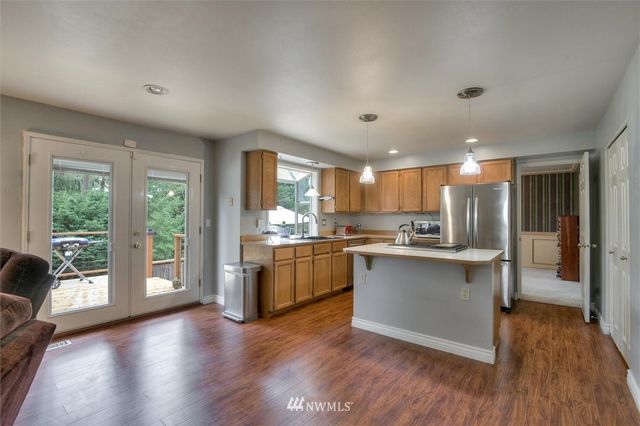 a kitchen with stainless steel appliances granite countertop a refrigerator a sink dishwasher a stove and white countertops with wooden floor