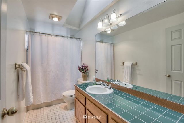 a bathroom with a granite countertop sink a toilet a mirror and shower