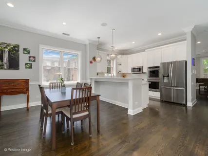 a kitchen with stainless steel appliances a dining table chairs refrigerator microwave and cabinets
