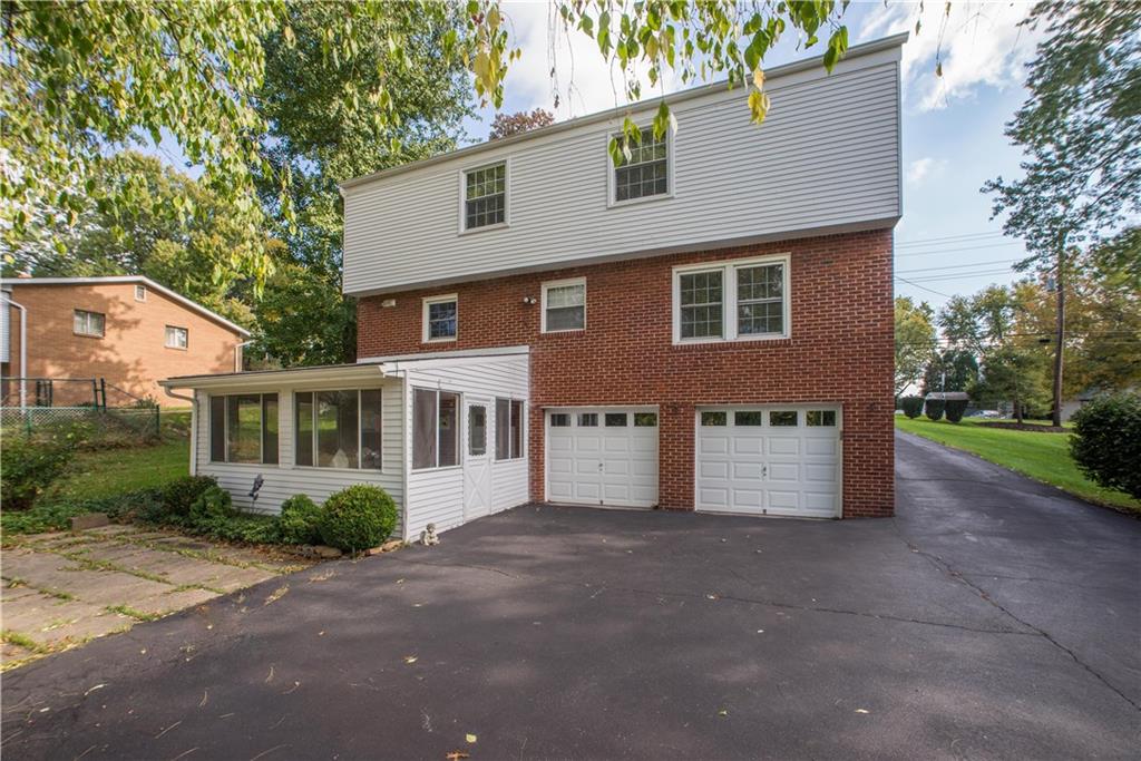 1484 Mayview Road Pittsburgh, PA 15241 - Photo 22 of 25 This view of the rear exterior shows an open patio area just off the enclosed patio. It is well-suited for outdoor grilling and dining. The home has newer garage doors and roof.