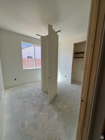 5005 North 75 East Enoch, UT 84721 - Photo 11 of 37 Unfurnished bedroom featuring a textured ceiling, concrete floors, and a spacious closet