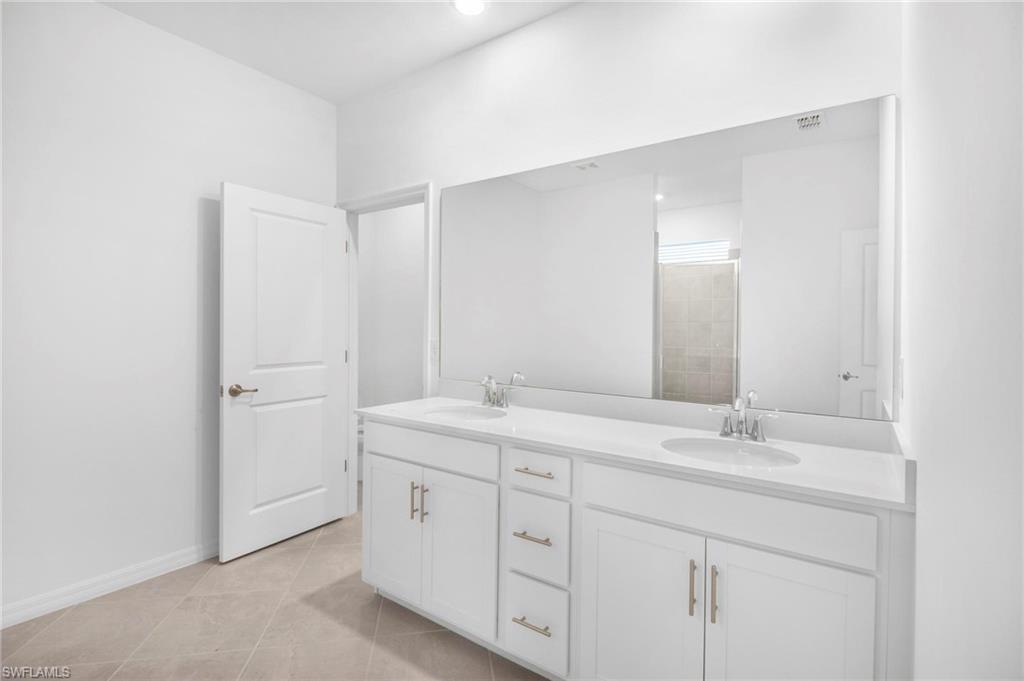 2265 Avocado Lane Naples, FL 34102 - Photo 13 of 32 a bathroom with a granite countertop sink two mirror and a vanity