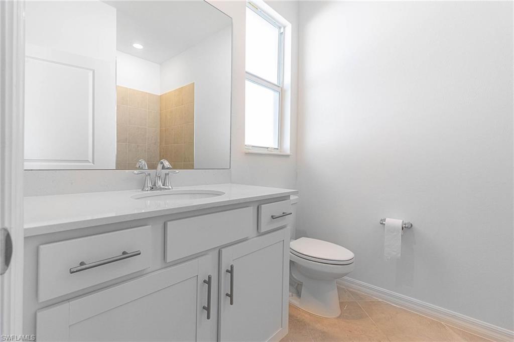 2265 Avocado Lane Naples, FL 34102 - Photo 19 of 32 a bathroom with a toilet a sink a mirror and a window