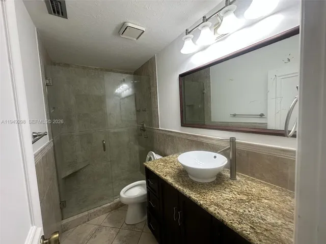 a bathroom with a granite countertop sink toilet a mirror and shower