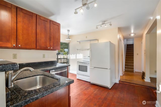 a kitchen with granite countertop a sink a stove and a refrigerator