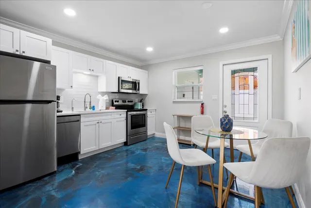 a kitchen with sink a refrigerator and chairs