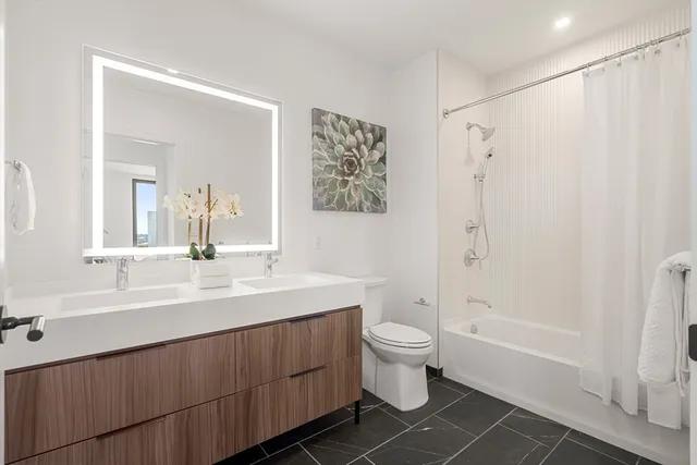 a bathroom with a double vanity sink toilet and shower