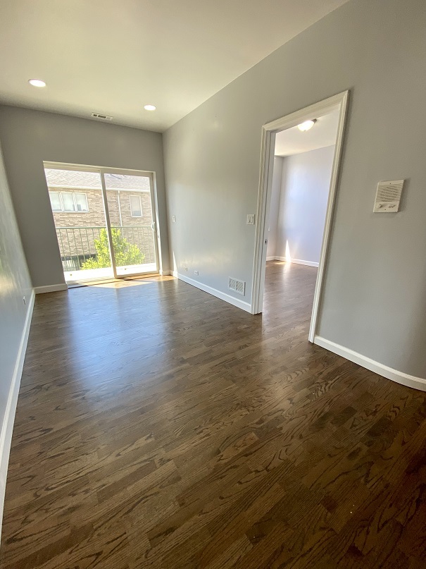 3131 South Benson Street, Unit 10 Chicago, IL 60608 - Photo 14 of 17 an empty room with wooden floor and windows