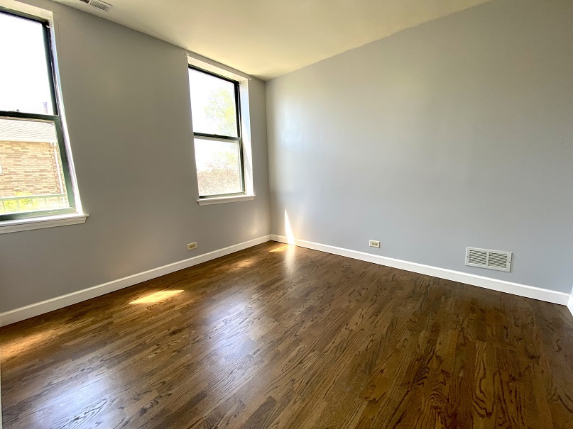 3131 South Benson Street, Unit 10 Chicago, IL 60608 - Photo 10 of 17 a view of an empty room with wooden floor and a window