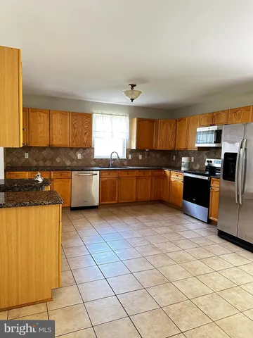 a large kitchen with granite countertop a stove top oven a sink a counter space and cabinets