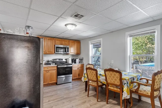 a kitchen with stainless steel appliances granite countertop a stove top oven a sink dishwasher a dining table and chairs with wooden floor