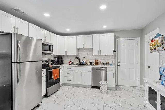 a kitchen with granite countertop stainless steel appliances a stove a sink and a refrigerator