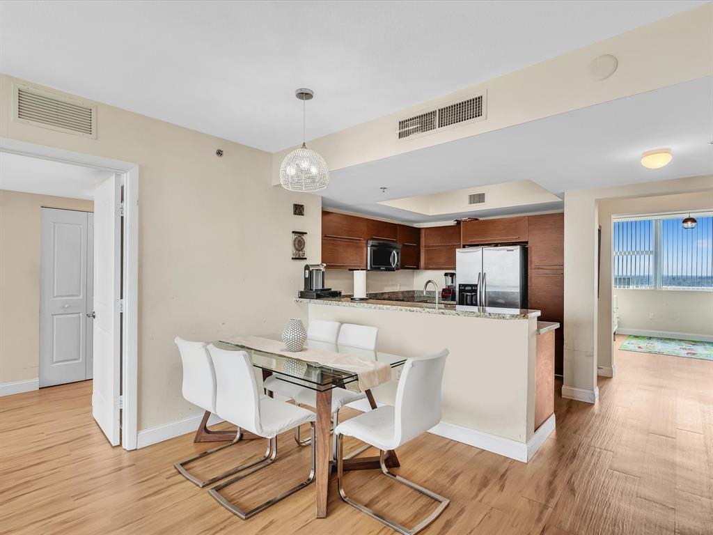2681 North Flamingo Road, Unit 2104S Fort Lauderdale, FL 33323 - Photo 16 of 99 a kitchen with stainless steel appliances kitchen island granite countertop a dining table chairs and a refrigerator