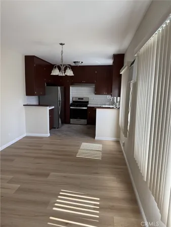 a kitchen with stainless steel appliances granite countertop a sink dishwasher a refrigerator and a stove with wooden floor