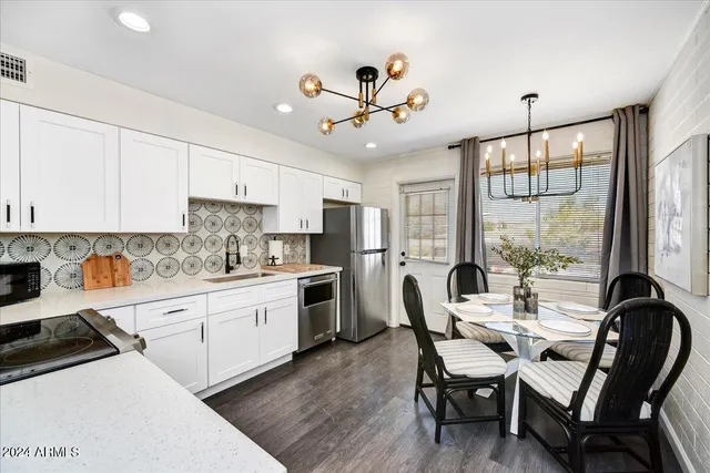 a kitchen with a dining table chairs stainless steel appliances and cabinets