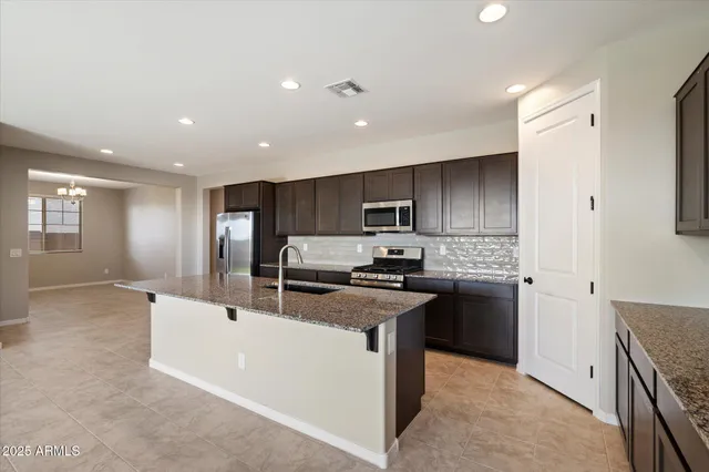 a kitchen with stainless steel appliances granite countertop a sink stove refrigerator and cabinets