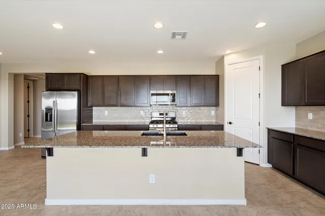 a large kitchen with stainless steel appliances granite countertop a sink a stove and a refrigerator