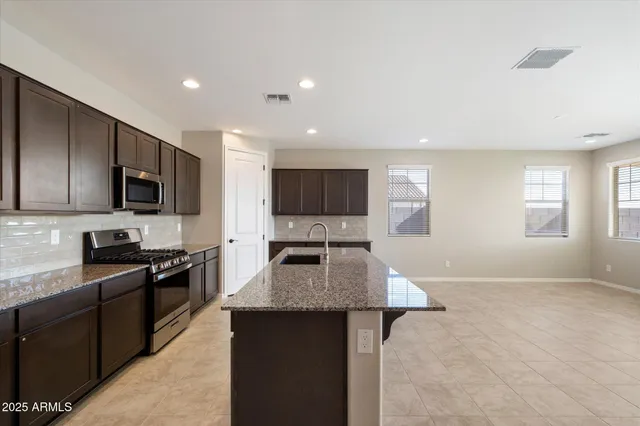a kitchen with stainless steel appliances granite countertop a stove top oven a sink dishwasher a microwave oven and a refrigerator with wooden floor
