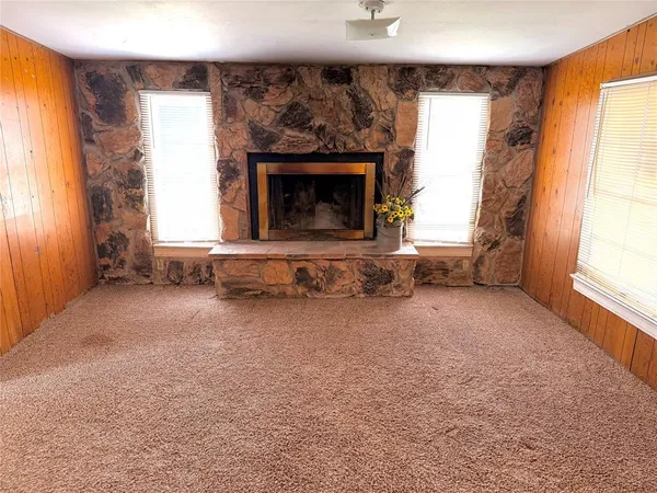 an empty room with windows and fireplace