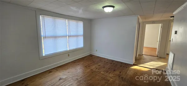 an empty room with wooden floor cabinet and window