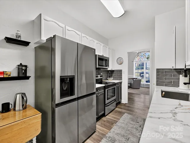 a kitchen with stainless steel appliances granite countertop a refrigerator a stove and a sink with wooden floor