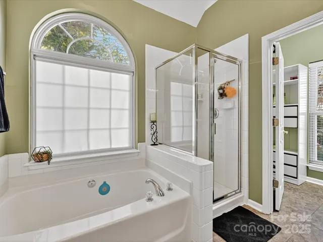 a bathroom with a tub a window and a shower