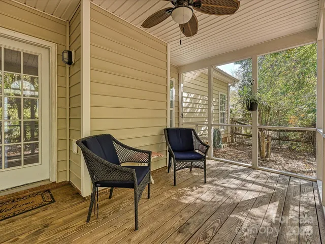 a living room with a floor to ceiling windows and a ceiling fan