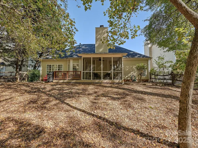 a view of a white house with a yard and large trees