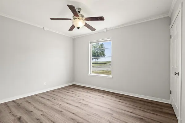 an empty room with wooden floor ceiling fan and windows