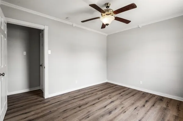 an empty room with wooden floor and a ceiling fan